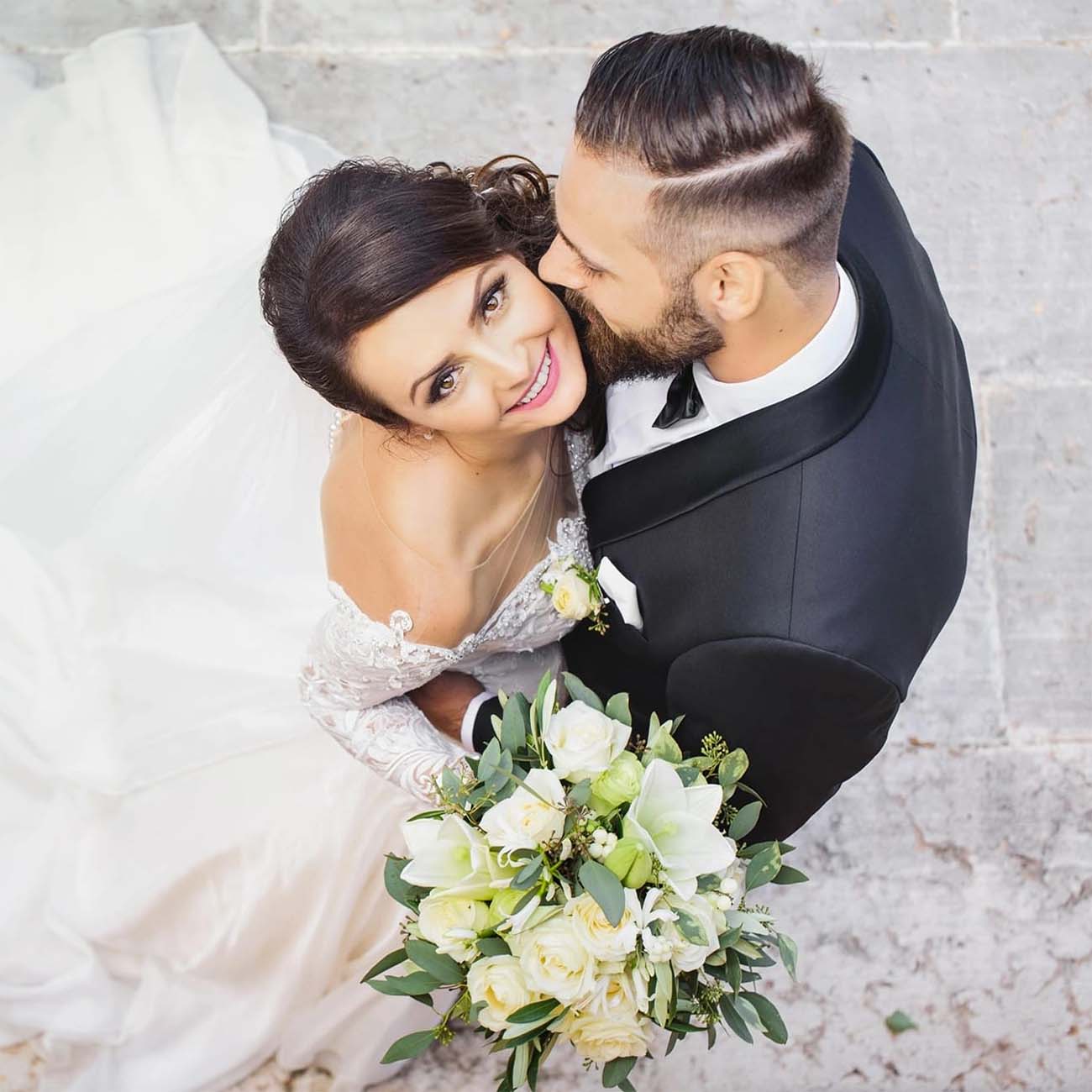 Happy bride in a wedding dress looking upward and smiling while embracing her groom