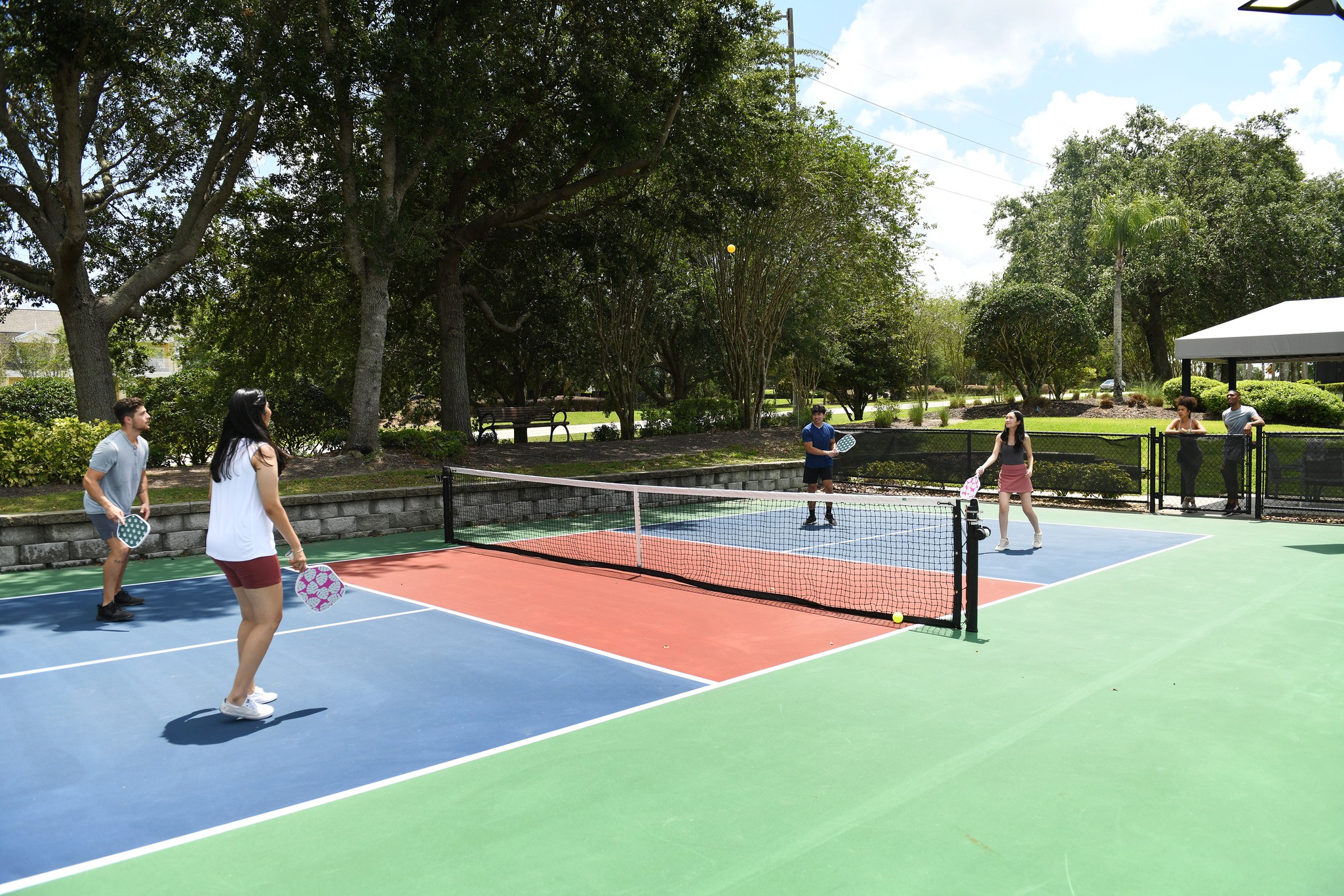 Group of players enjoying a game of pickleball on outdoor courts under the sun