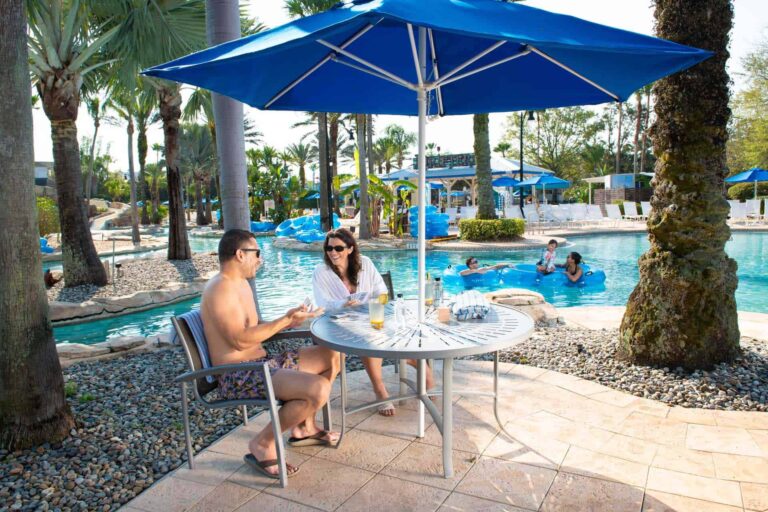 Happy couple sitting together at a covered table next to the water park lazy river