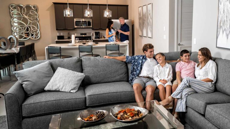 Family relaxing together on a large sectional sofa at a Rentyl at Reunion condo